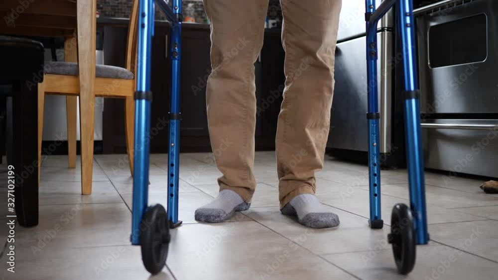 At home, a disabled older man walking with a walker slowly in his ...