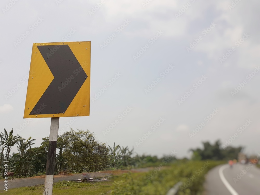 Black colour right curve sign on yellow plate at the highway