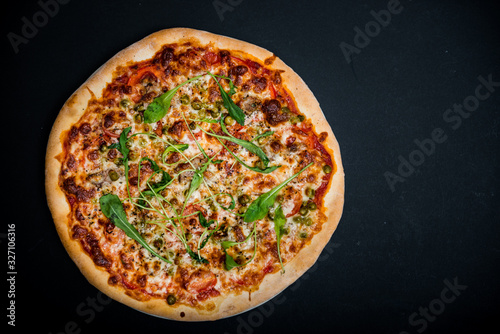 Italian pizza with greens on the black table with copy space