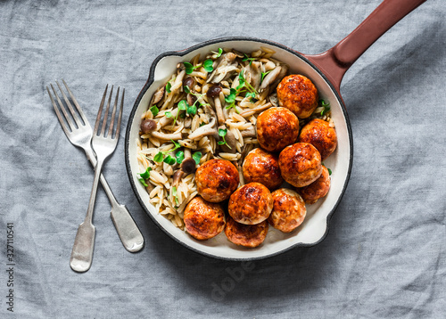 Orzo mushrooms pasta with teriyaki sauce chicken baked meatballs in a pan on a gray background, top view