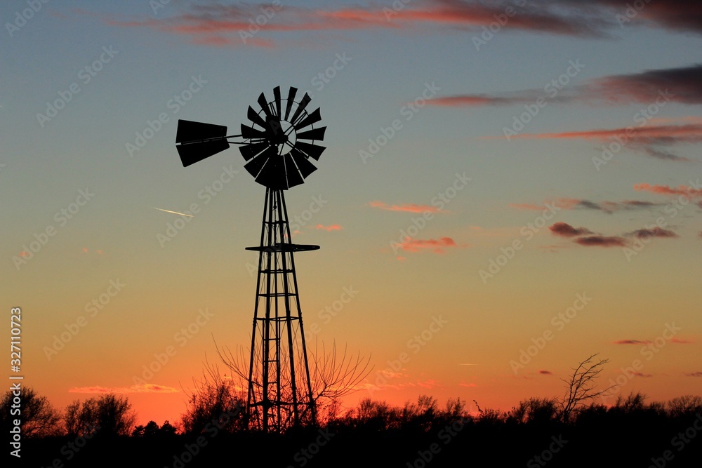 Kansas colorful Sunset with tree's,clouds, and a Windmill silhouette north of Hutchinson Kansas USA out in the country. Kansas colorful Sunset with tree's,clouds, and a Windmill silhouette north of Hutchinson Kansas USA out in the country.