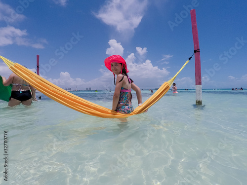 Playing on a hammock in the beautiful clear waters of Cancun, Mexico.