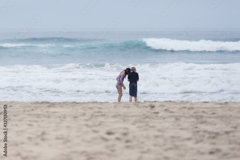 A girl is playing in the sand at a California beach.