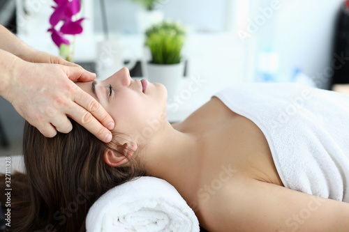 Hands massage whiskey to girl who lying on towel. Woman worried about insomnia, normalization sleep. Relieve muscle tension after heavy physical exertion or difficult day. Gentle caring hands master