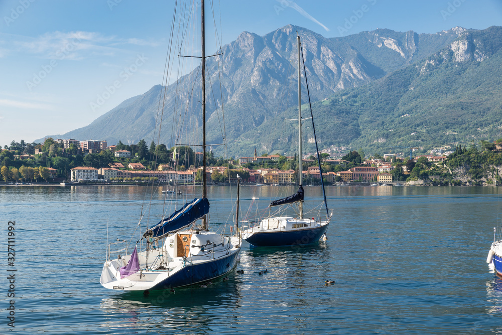 Boats moored on lake. Como lake, Italy. Panorama from the lakeside of the city of Lecco towards the village of Malgrate. Large and famous European lake located in northern Italy