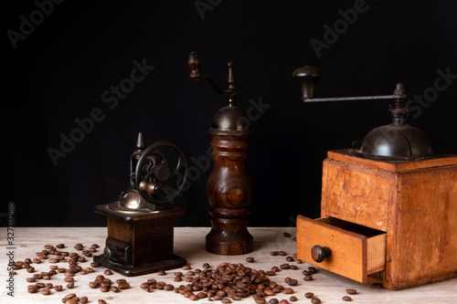 Wooden vintage manual coffee mills and pepper mill with coffee beans scattered on a wooden surface