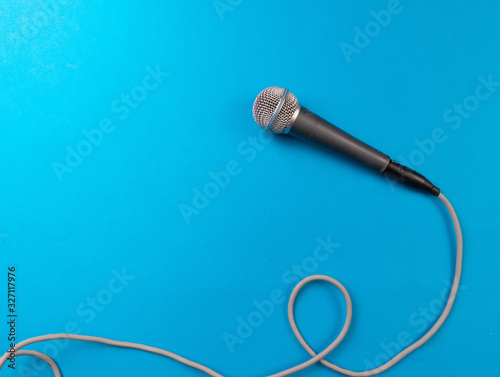 Dynamic microphone with a long gray wire against turquoise background, professional equipment