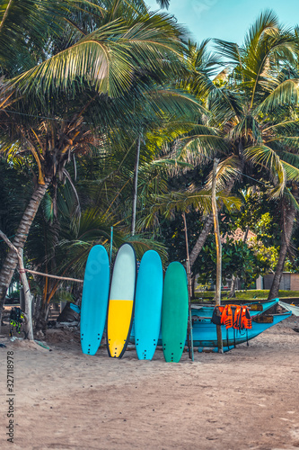 Surfboards resting on a wooden stand in the sand at a surf station in Sri Lanka Hikkaduwa