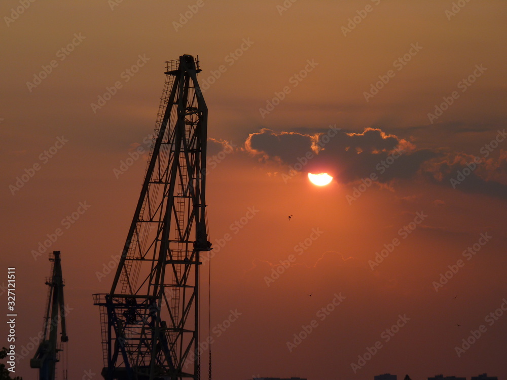 two port cranes at sunset