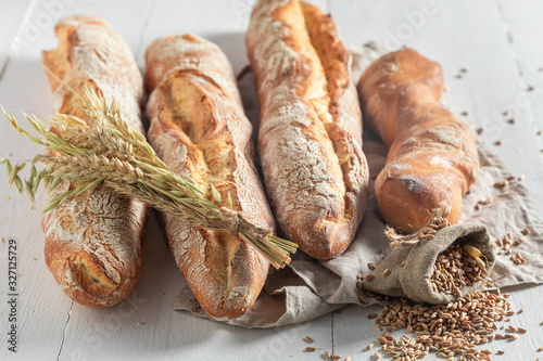 Homemade golden baguettes with grains and ears of wheat photo