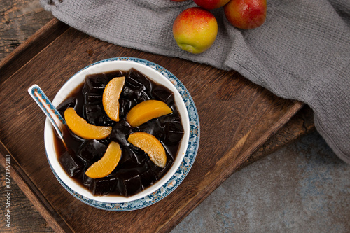 Black Grass Jelly Mesona chinensis, vegetable jelly, black in color, eaten with sugar. Pieces of grass jelly cut in bowl with colorful fruits on top (known as chaokuai, suong sao ) photo