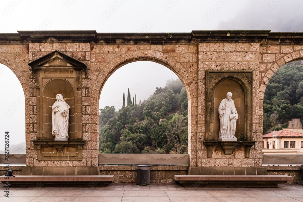 Fototapeta premium Arch of Montserrat Monastery in foggy winter day. Hiking religious destination.