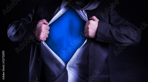 Superhero, young businessman tearing his shirt off isolated on dark background with copy space