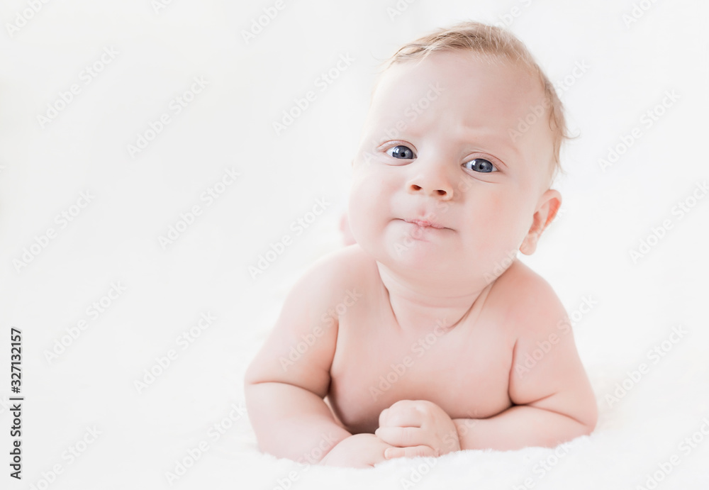 four month old white boy with blue eyes lying on his stomach on a white background four month old white boy with blue eyes lying on his stomach on a white background