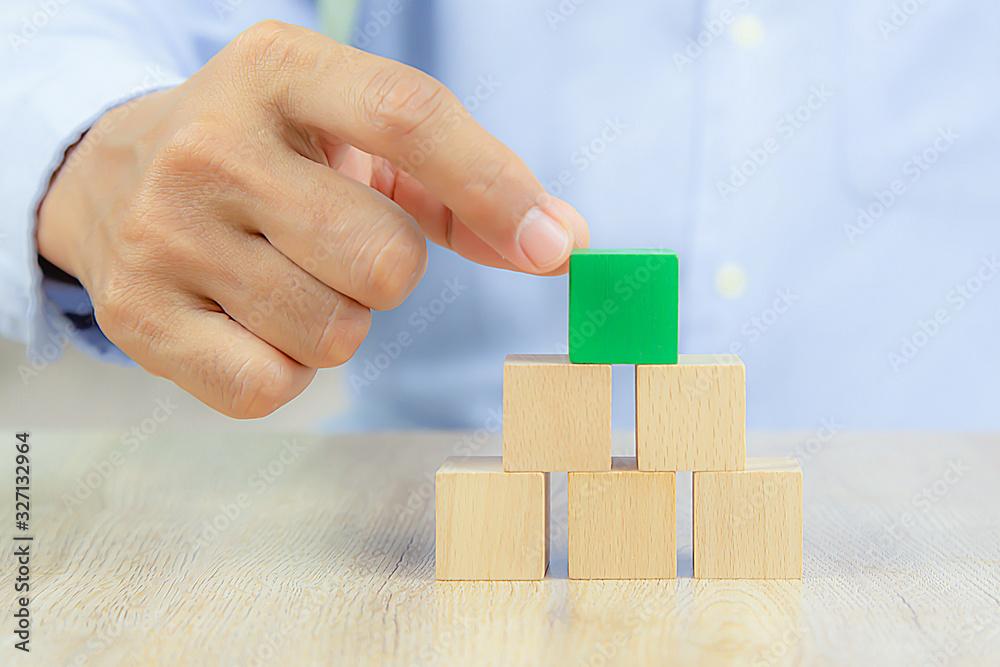 Close-up hand choose a cube shape wooden block toy stacked without graphics for Business design concept and activity for child foundation practice skills. Close-up hand choose a cube shape wooden block toy stacked without graphics for Business design concept and activity for child foundation practice skills.