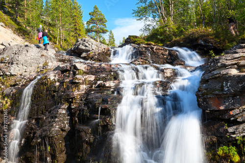 Man end woman hikers standing next to beautiful waterfall in Khibiny mountains. The Kola peninsula  Russia