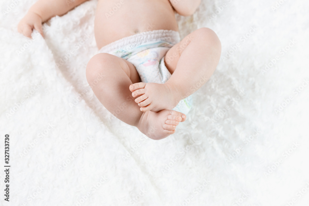 feet of a six months old baby wearing diapers lying on the bed feet of a six months old baby wearing diapers lying on the bed