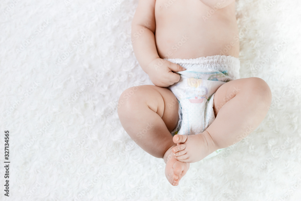 feet of a six months old baby wearing diapers lying on the bed feet of a six months old baby wearing diapers lying on the bed