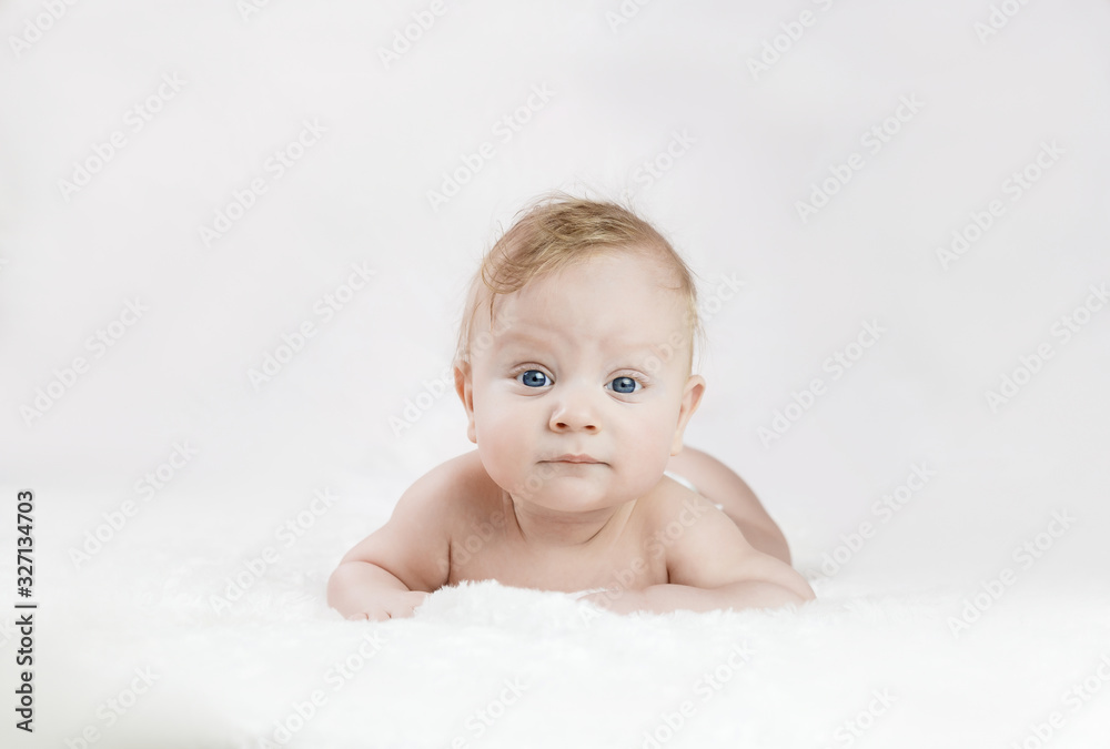 five-month-old blond boy with blue eyes lies on his stomach on a white background five-month-old blond boy with blue eyes lies on his stomach on a white background