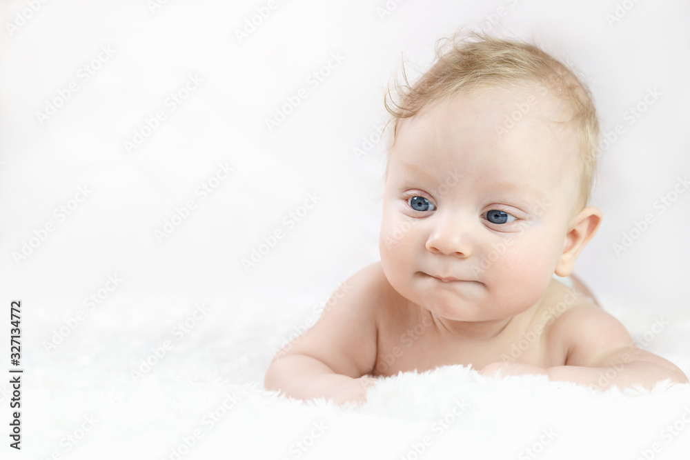 five-month-old blond boy with blue eyes lies on his stomach on a white background five-month-old blond boy with blue eyes lies on his stomach on a white background