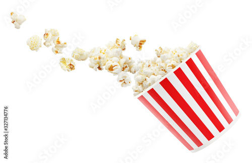 Tasty popcorn falling out of a red striped carton bucket, isolated on white background