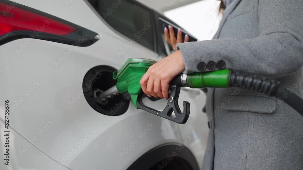 Woman using smartphone while her car is refueling. Slow motion Woman using smartphone while her car is refueling. Slow motion