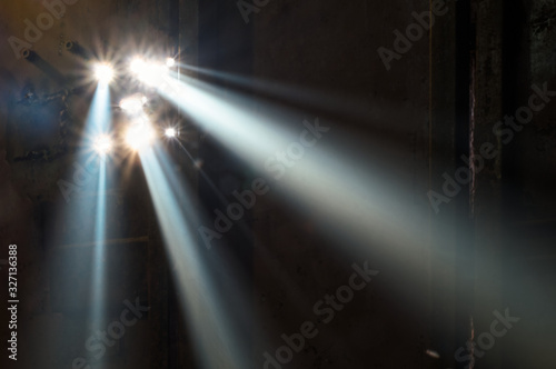 A sunbeam shines through the holes in the iron door. Horizontally. Targeted direct rays of light pass through the fog and create the effect of a multiple spotlight.