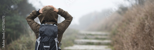 Woman hiker walking on trail at foggy mountain top