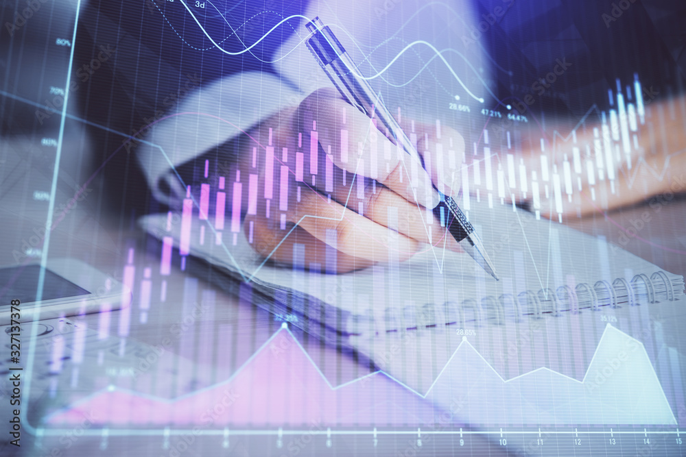 A woman hands writing information about stock market in notepad. Forex chart holograms in front. Concept of research. Multi exposure A woman hands writing information about stock market in notepad. Forex chart holograms in front. Concept of research. Multi exposure