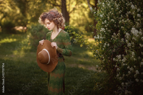 portrait of a young beautiful girl with curly hair in a hat on a green background with natural light