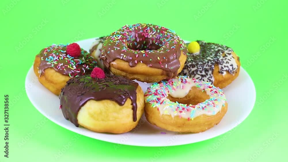 Donuts with glazed chocolate and crumbs served on white plate on green screen 