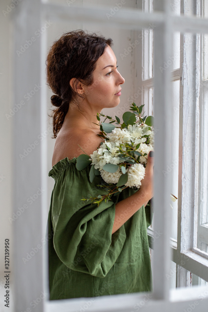 vertical portrait of a beautiful dark-haired European sadly standing at the window vertical portrait of a beautiful dark-haired European sadly standing at the window