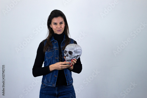 serious  middle age woman with skull, long face, with a serious look on his face, isolated on gray background studio shotblack sweater, denim jacket, jeans. Place for your text in copy space. photo