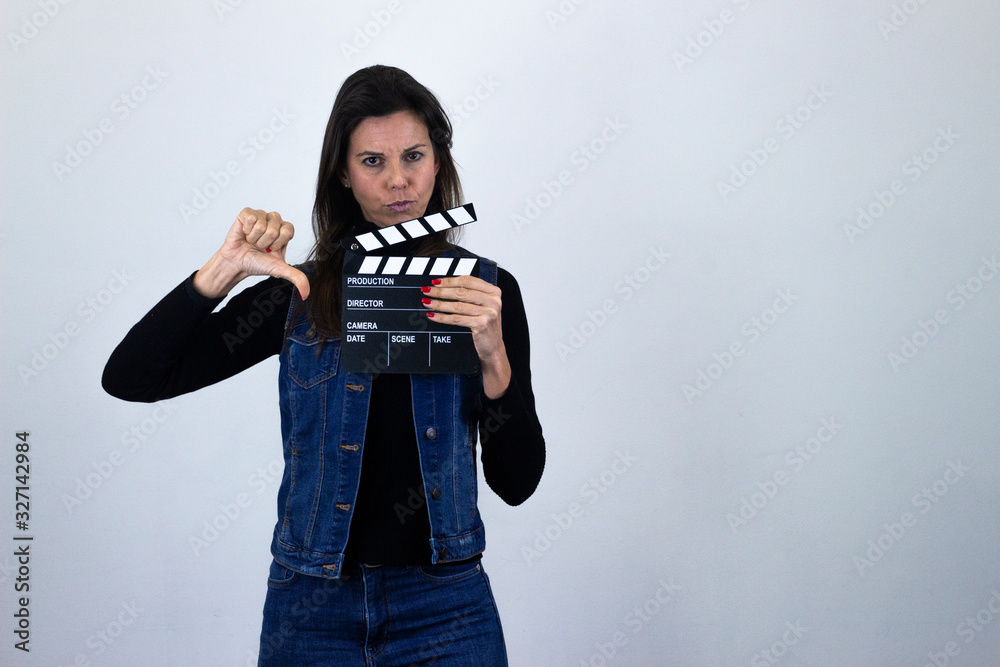 pretty middle age woman with clipper board and negative assessment symbol  thumb down, isolated on gray background studio shotblack sweater, denim  jacket, jeans. Place for your text in copy space. Stock Photo