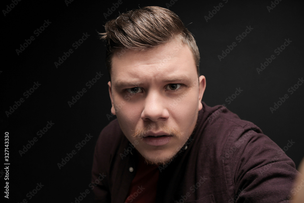 Portrait of young puzzled man isolated on gray background