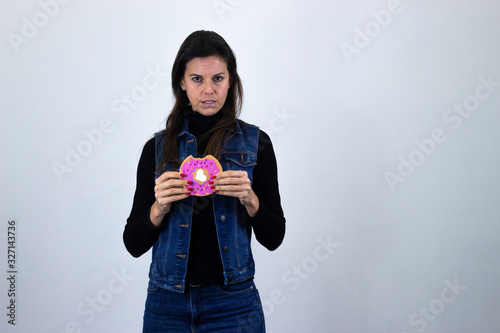pretty  middle age woman model with cookie showing thumbs up gesture, isolated on gray background studio shotblack sweater, denim jacket, jeans. Place for your text in copy space. photo