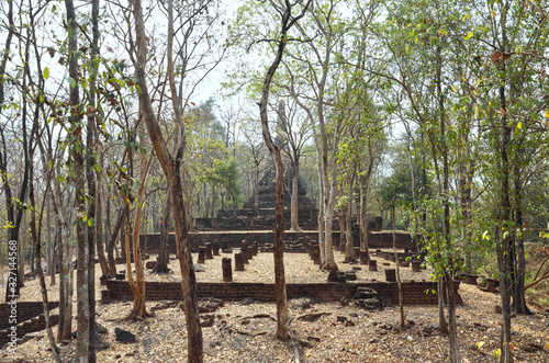 Fototapeta Naklejka Na Ścianę i Meble -  Ruins of Ancient Thai Temple (Wat Chedi Kao Yod). Trees grow between ancient stones. Si Satchanalai historical park, Northern Thailand.