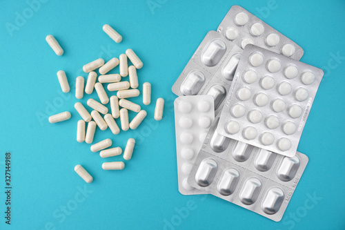 White pharmaceutical medicine capsules with blister pack, asthma inhaler, medical bottle on blue background.Medical, pharmacy and healthcare concept. Copy space for your text 