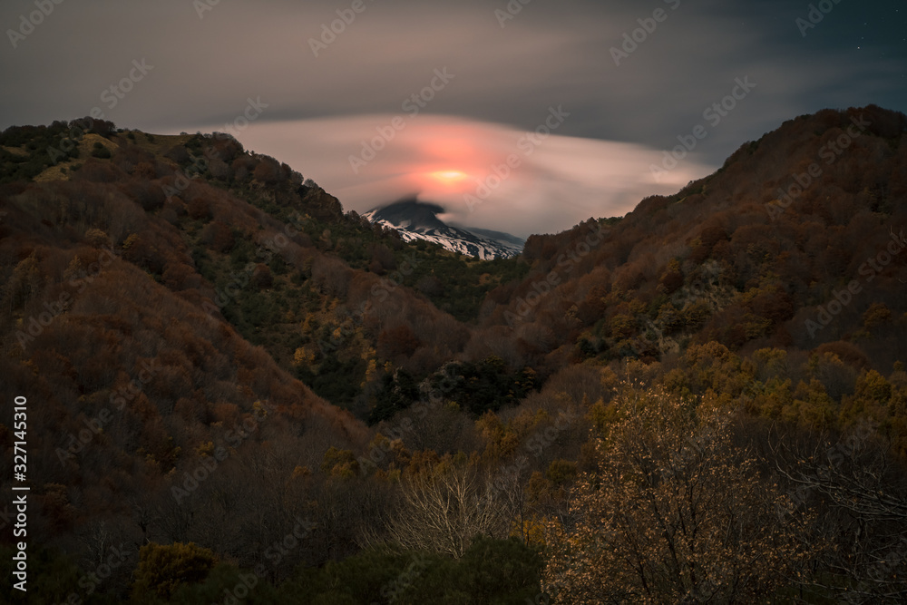 Volcano Etna eruption at night, full moon illuminating the landscape, Bove Valley, Sicily.