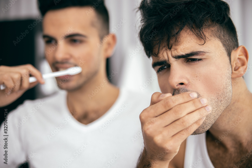 Two young men brushing teeth in the bathroom Two young men brushing teeth in the bathroom