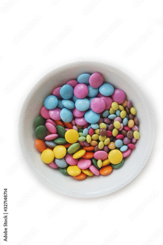 Chocolate candies with coloful glazes in a white bowl isolated on white background Chocolate candies with coloful glazes in a white bowl isolated on white background