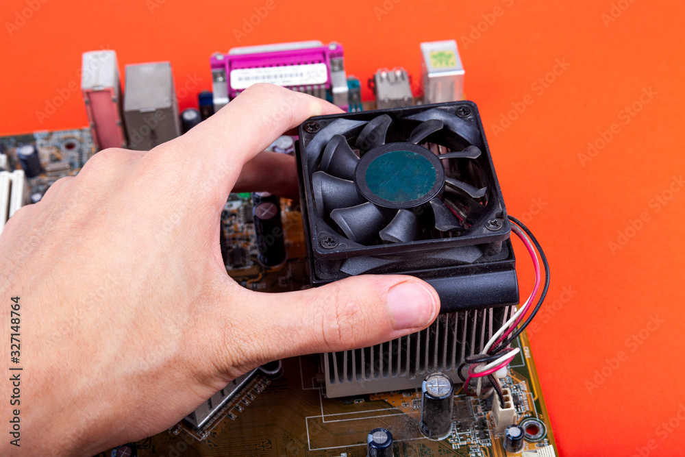 Removing an small old CPU cooler from the motherboard. Human hand
