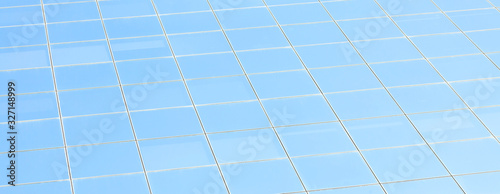 Office building facade, clean square glass blue window panes abstract background texture Simple square glass pane pattern with soft light reflections, no clouds, corporate building light blue backdrop