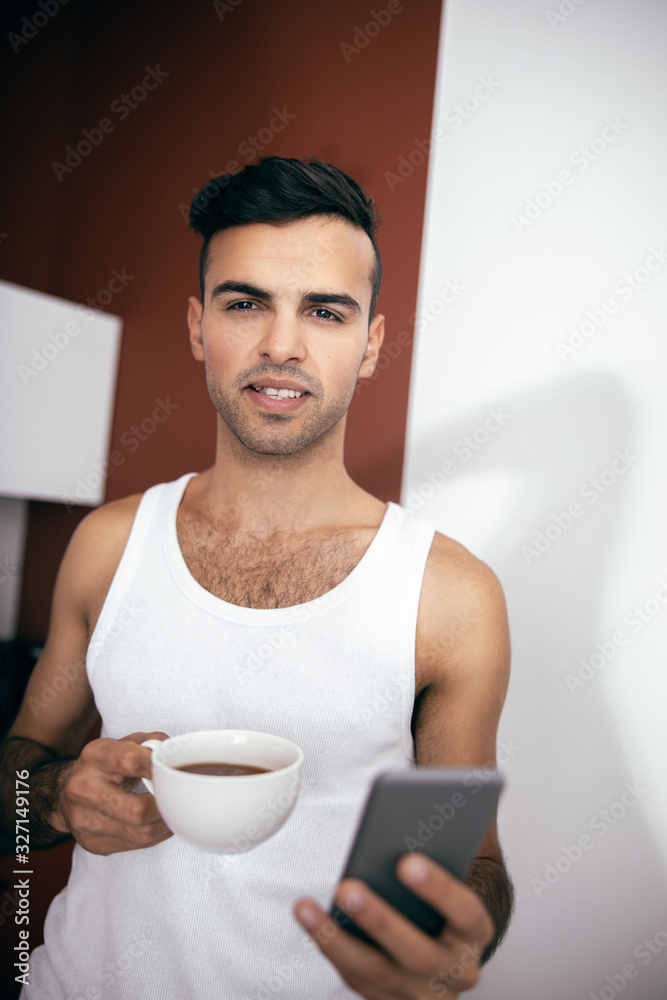 Cheerful man holding mobile phone at the kitchen Cheerful man holding mobile phone at the kitchen