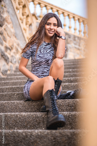 A smiling pretty brunette sitting on some stairs