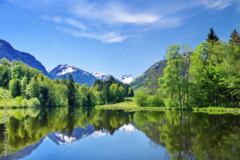 Bergsee im Frühling in den Alpen mit Gipfel und Schnee Bergsee im Frühling in den Alpen mit Gipfel und Schnee