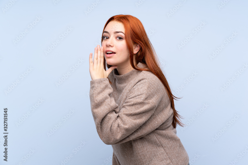 Redhead teenager girl with sweater over isolated blue background whispering something Redhead teenager girl with sweater over isolated blue background whispering something