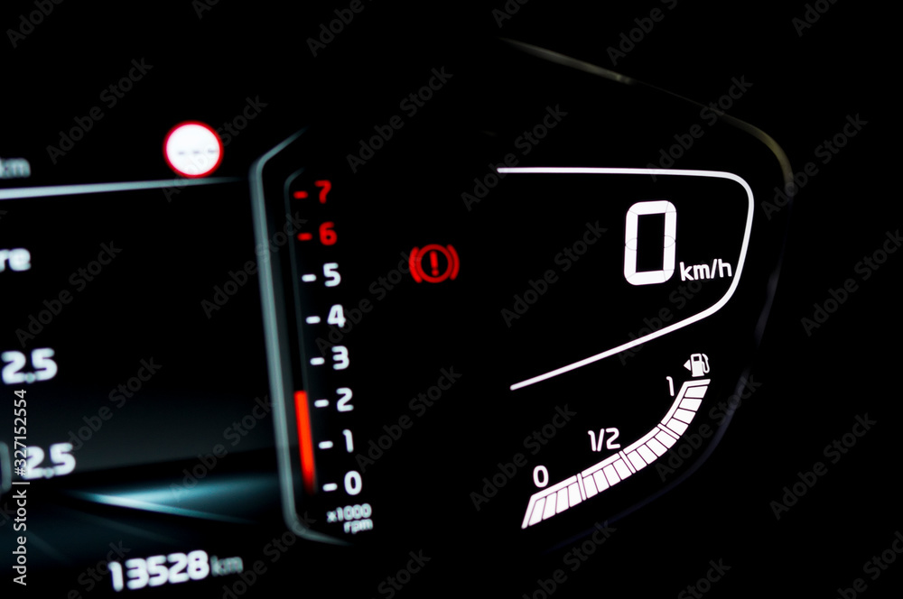 Close up of side view of illuminated full digital car dashboard panel with speedometer, tachometer, odometer and fuel level gauge in hybrid vehicle. Modern electronic instrument cluster in modern car. Close up of side view of illuminated full digital car dashboard panel with speedometer, tachometer, odometer and fuel level gauge in hybrid vehicle. Modern electronic instrument cluster in modern car.
