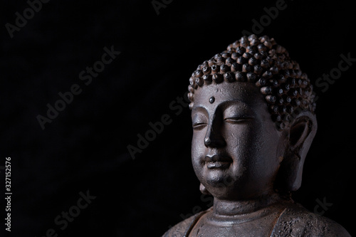 Meditating Buddha Statue isolated on black background. Copy space.