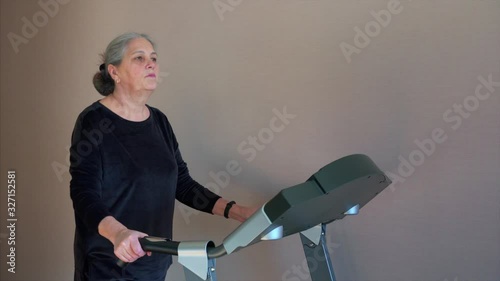 Fit senior woman at home on treadmill doing cardio work out.